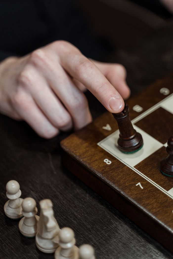 About Close-up of a hand moving a chess piece, highlighting strategy and concentration.