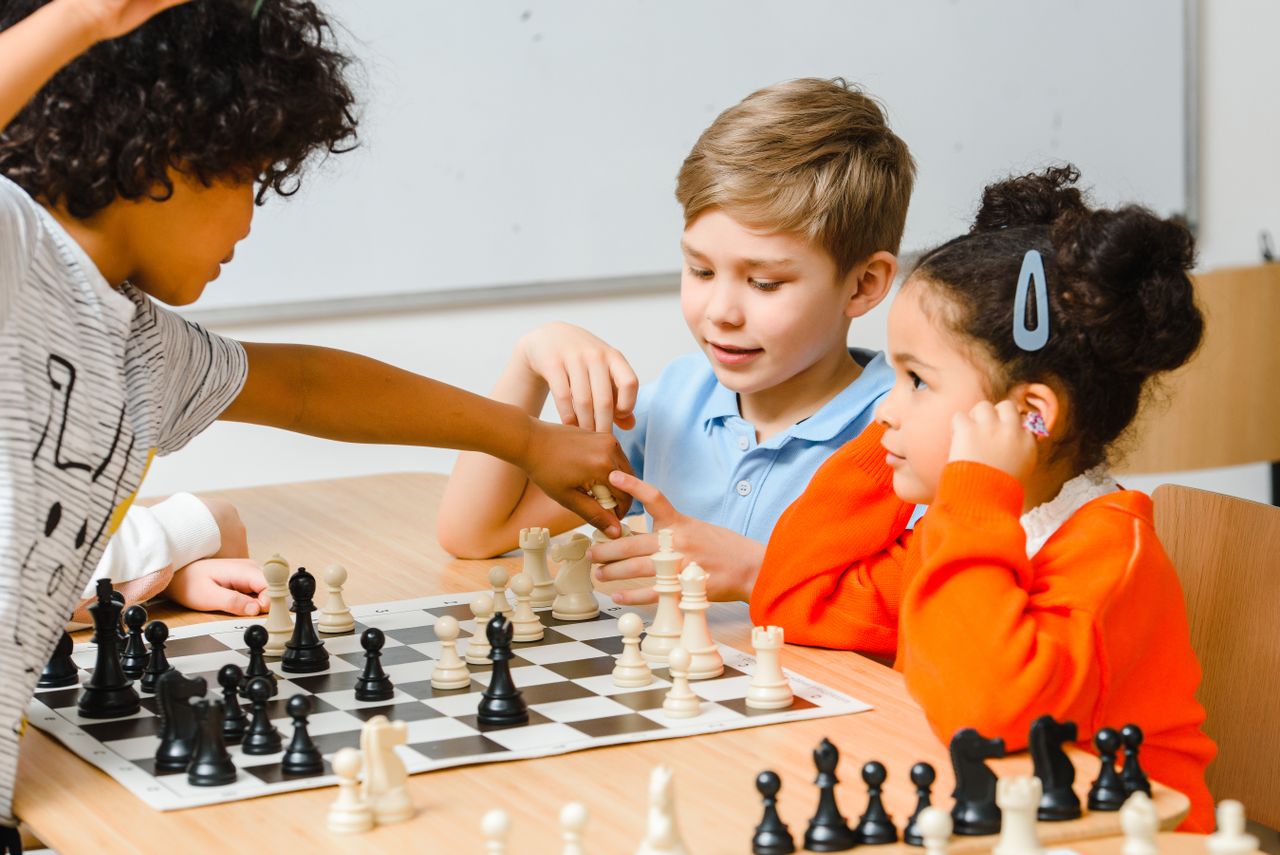 Services Group of diverse children engaged in a chess game, enhancing strategy skills.